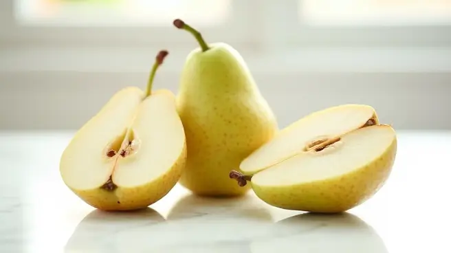 Gele peren, waarvan één hele en twee halve, liggen op een tafel.